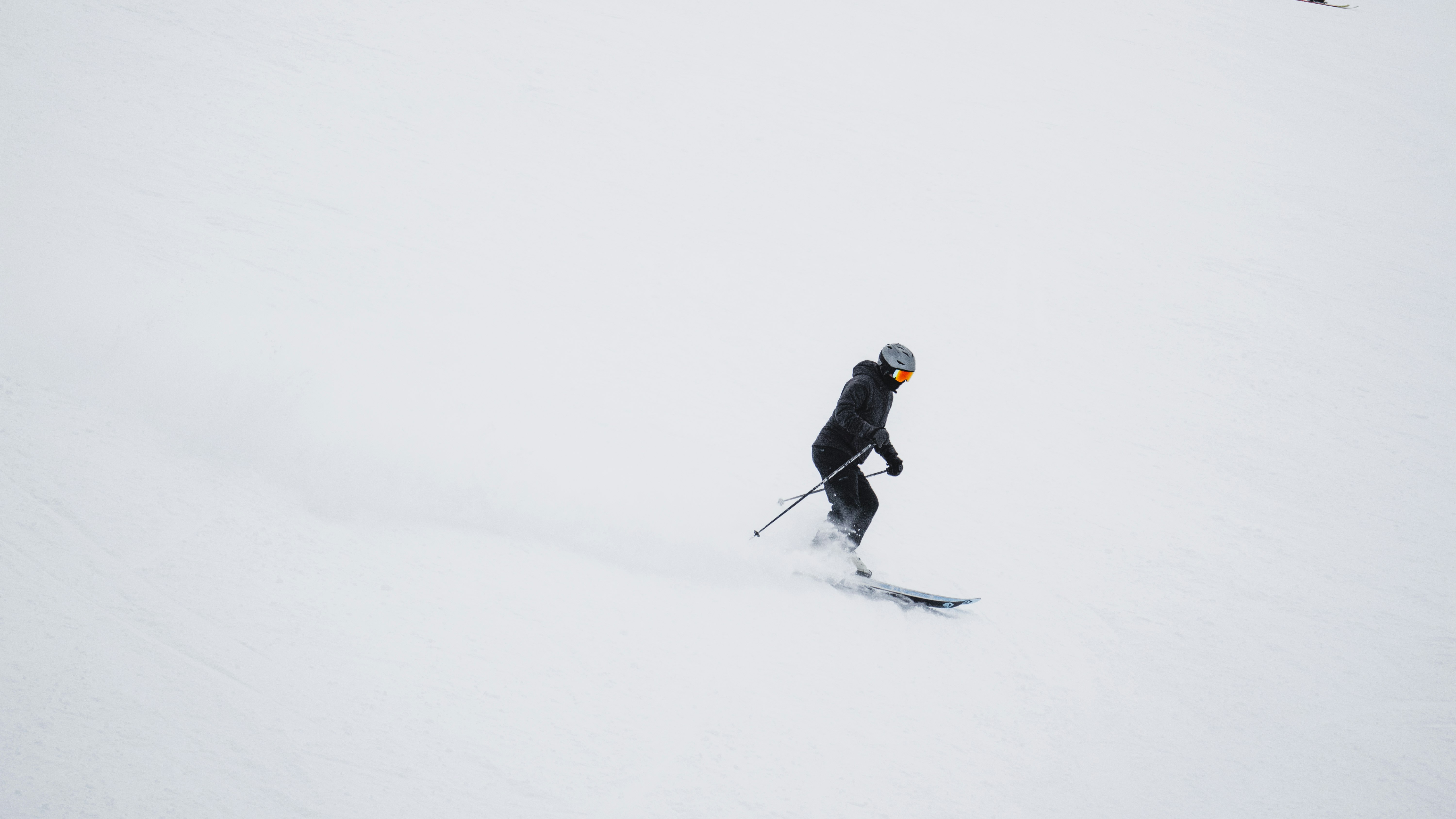 man in black jacket and black pants riding ski blades on snow covered ground during daytime